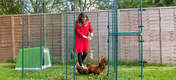 Omlet green Eglu Go plast hønsegård i Omlet walk in chicken run med kyllinger og dame som holder Omlet Caddi