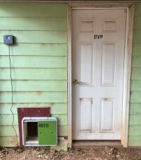 En automatisk kyllingdøråpner festet til utsiden av huset