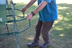 En person som viser hvordan man bruker håndtakene for å flytte hønsegården