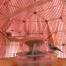 En modellfugl satt på en mater inne i et rosa fuglebur med et speil