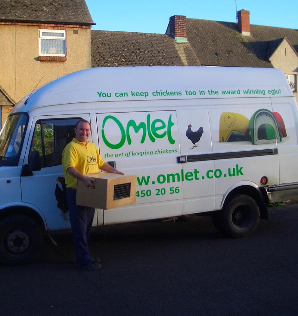 En budbilsjåfør ved siden av en varebil av merket Omlet med en kasse kyllinger.
